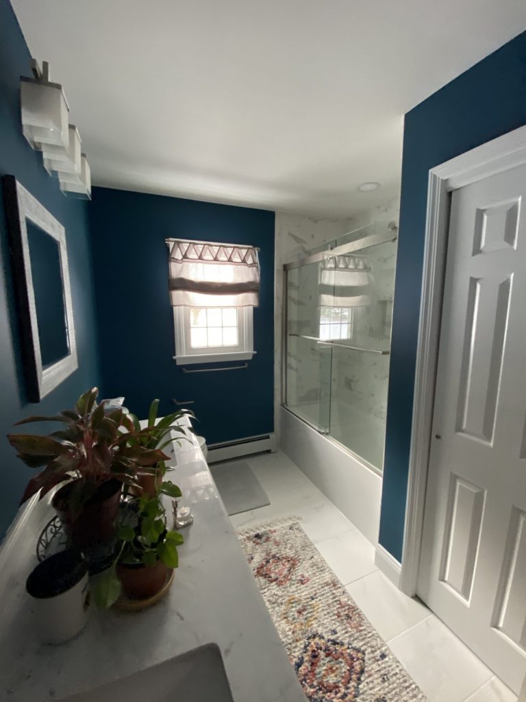 bathroom with blue walls, carpet on floor, glass door shower